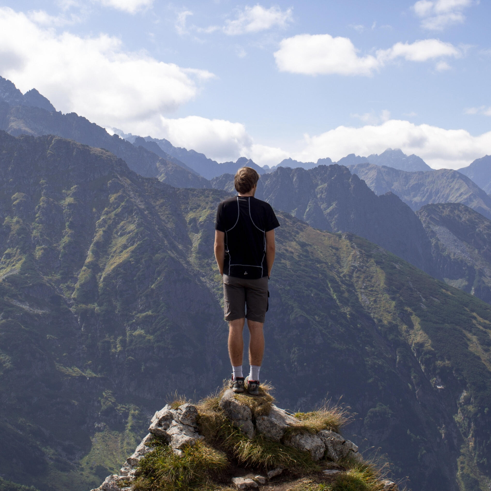 A man standing on the edge of a cliff looking out over the rugged terrain before him.